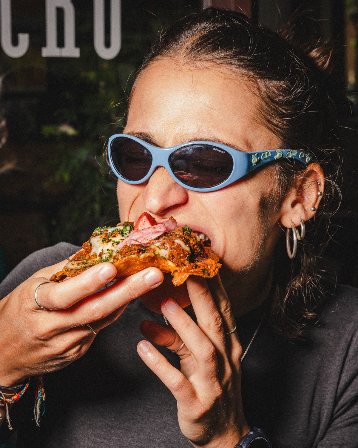 una ragazza con gli occhiali da sole addenta una pizza