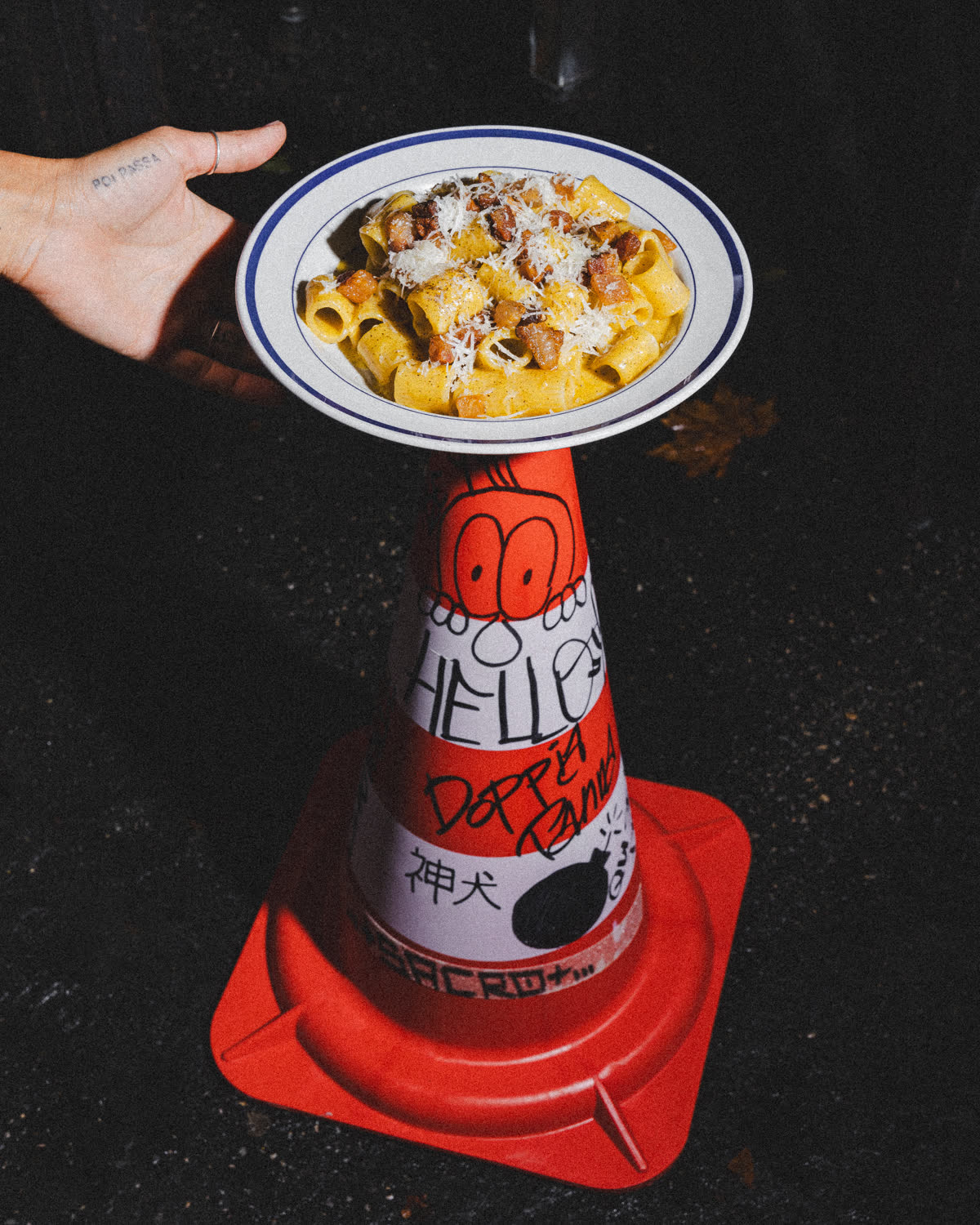 un piatto di pasta in equilibrio su un cono stradale dipinto